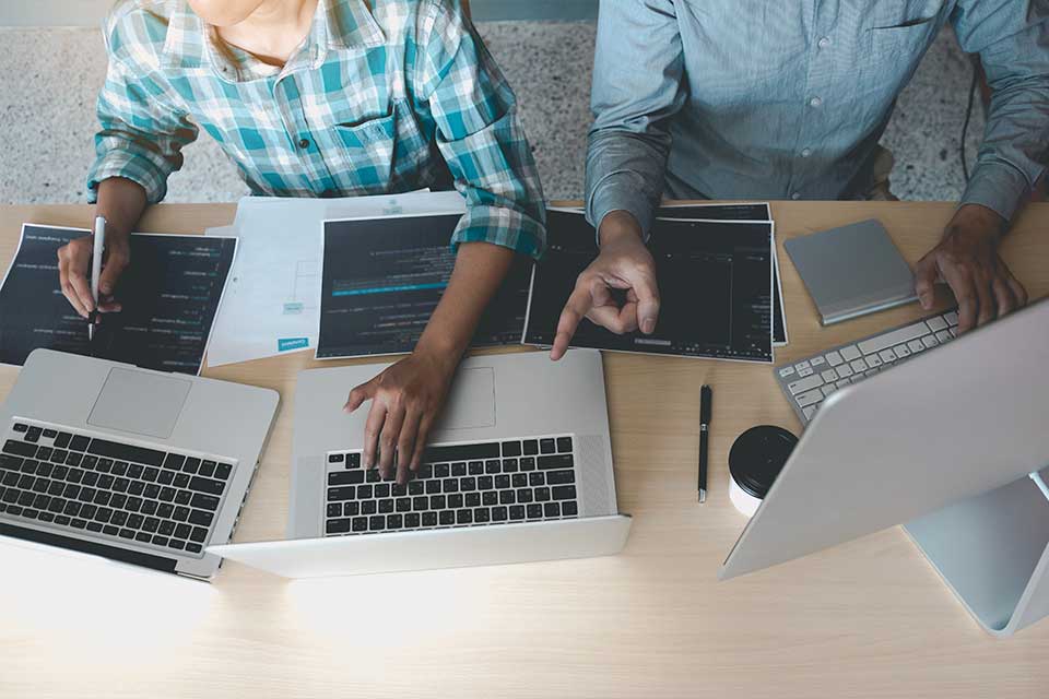 programmers working across 3 laptops at a desk
