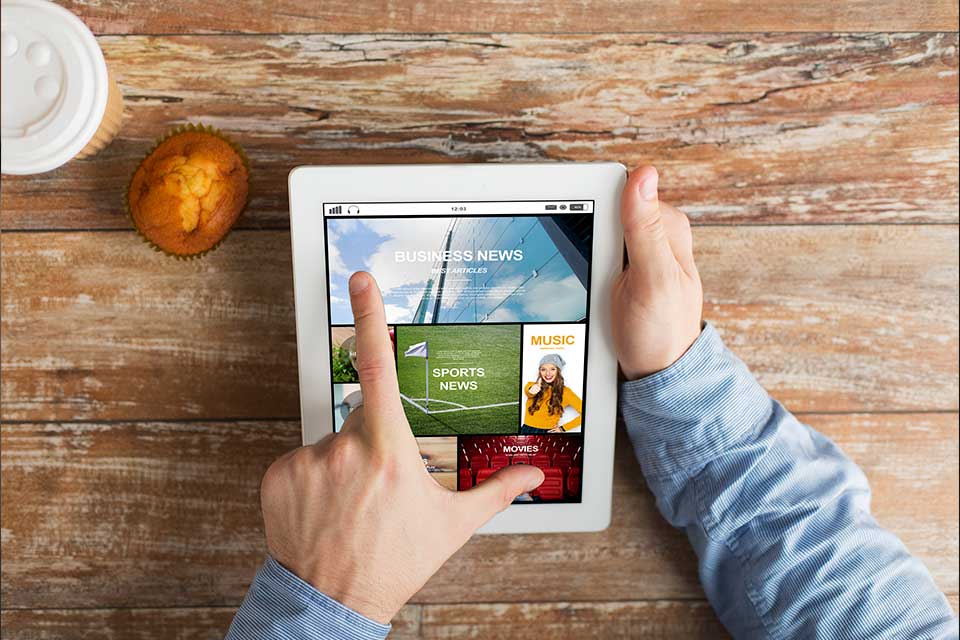 person using tablet at table browsing news app