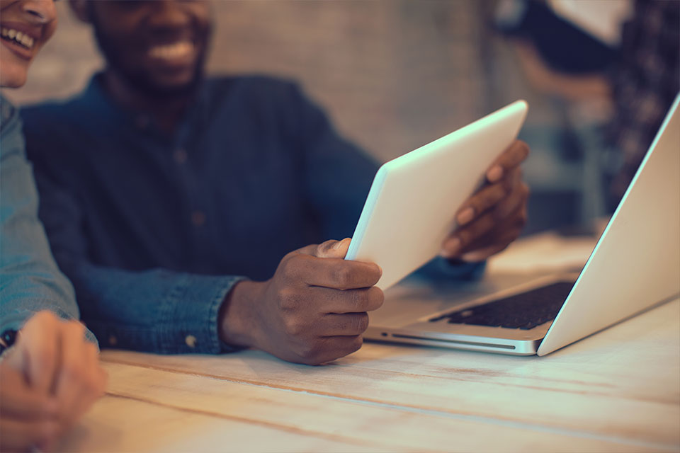man and woman using tablet at a computer desk